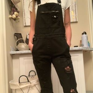 Skinny black jean overalls.